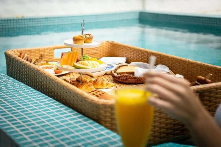 Floating breakfast tray with fruit, pastries and juice in a swimming pool